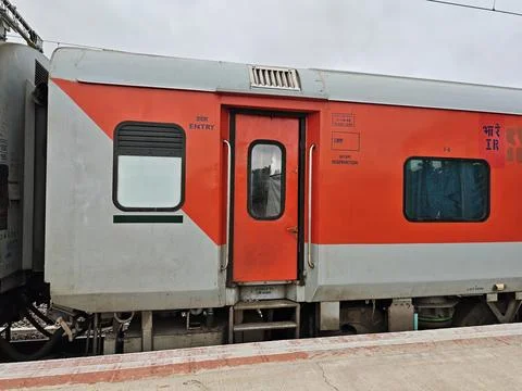 An Indian Railways LHB second AC coach painted in vibrant red and grey stan.. Stock Photos