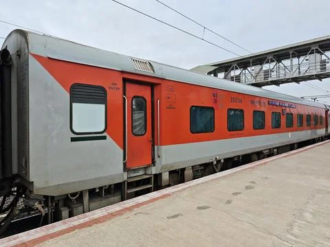 An Indian Railways LHB second AC coach painted in vibrant red and grey stan.. Stock Photos