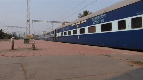 Indian Railways passenger train speeding and crossing railway station with speed Stock Footage 98575491