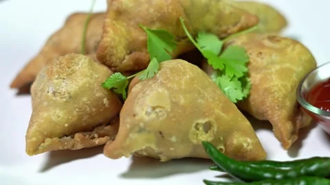 Indian samosas (Indian triangular pastry) rotating on a white plate. Stock Footage 323967433