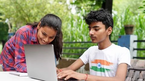 Indian School kids E-learning using laptop. Children doing homework at gard.. Stock Photos