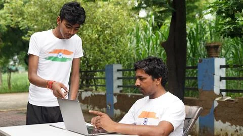 Indian School kids E-learning using laptop. Children doing homework at gard.. Stock Photos