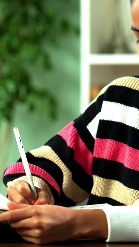 Indian schoolgirl writing in a notebook while sitting at home 스톡 동영상 343214327