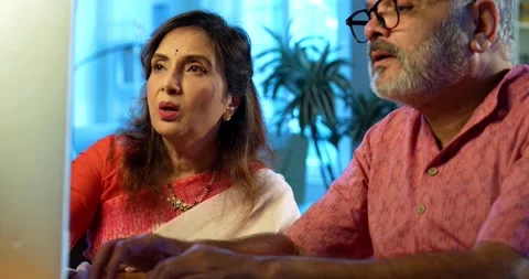 Indian senior couple using computer at home for work, accounting Stock Footage 343111666