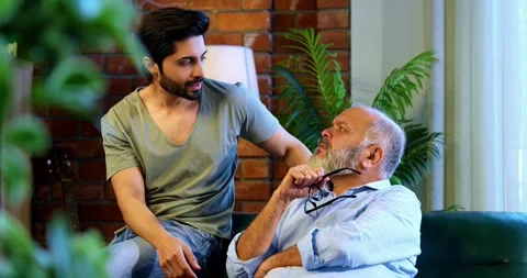 Indian senior Father Son Sharing Heartfelt Conversation At Home sitting on sofa Stock Footage 342778348