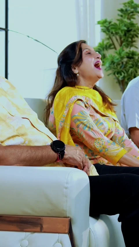 Indian senior laughing at home while seated on sofa with friend Stock Footage 342387239