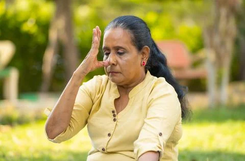 Indian senior woman doing nostril breathing exercise or pranayama yoga with eyes Stock Photos