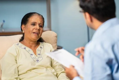 Indian senior woman explaining problems to psychologist during counselling at Stock Photos