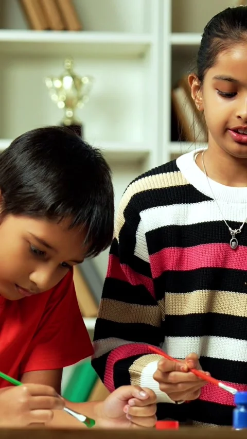 Indian siblings exploring creativity by painting on a drawing paper at home Stock Footage 343214444