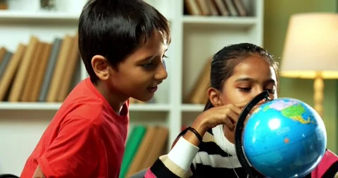Indian siblings playing with an educational globe at home Stock Footage 343215568