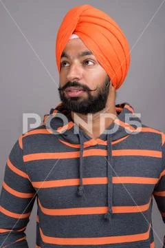 Indian Sikh man wearing orange turban while thinking Stock Photos