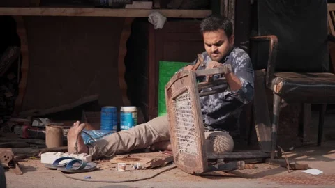 Indian skilled carpenter busy fixing a vintage chair in a furniture workshop Stock Footage 329098128
