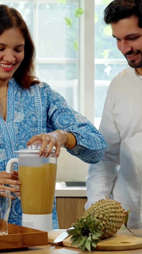 Indian smart young couple making healthy juice in kitchen Video stock 343416150