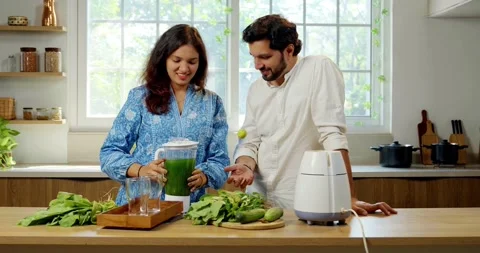 Indian smart young couple making healthy juice in kitchen Video stock 343490641