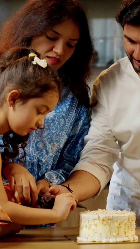 Indian smart young couple with small daughter decorating cake Stock Footage 343416238