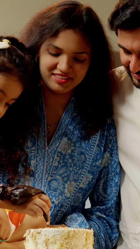 Indian smart young couple with small daughter decorating cake Stock Footage 343416286
