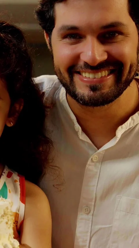 Indian smart young couple with small daughter decorating cake Video stock 343416323