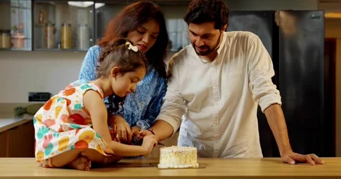 Indian smart young couple with small daughter decorating cake Stock Footage 343491017