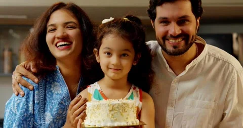 Indian smart young couple with small daughter decorating cake Stock Footage 343492065