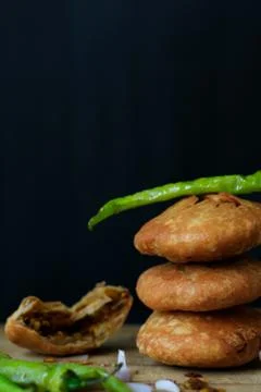 Indian snack kachori served with green chilli and onions in a black backgroun Stock Photos