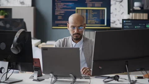 Indian Software Engineer Coding on Laptop with Multiple Monitors in Office Vidéo 337477521