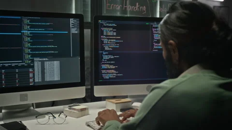 Indian Software Engineer Typing Code on Dual Monitors in Office Stockbeeldmateriaal 348363258