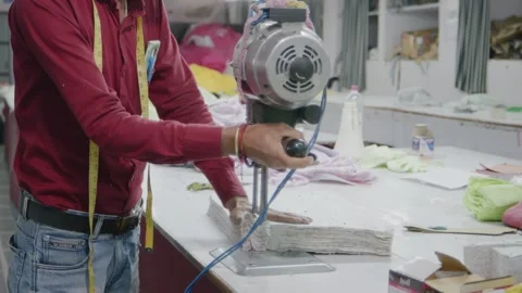 Indian tailor cutting clothes with a specialized machine in garment factory Stock Footage 243633074