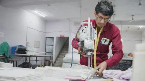 Indian tailor man cutting a bunch of fabric with a specialized textile machine Stock Footage 243632926