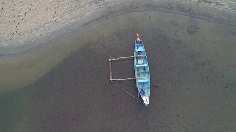 Indian traditional dinghy with side float anchored on a shallow river. Aerial. Stock Footage 85199038