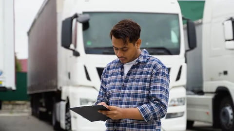 Indian truck driver checking shipment list while standing on parking lot of Stock Footage 251837408