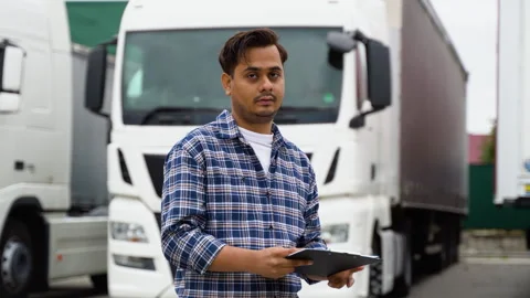 Indian truck driver checking shipment list while standing on parking lot of Stock Footage 251837657