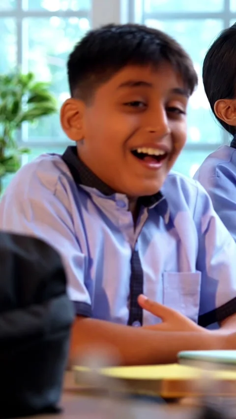 Indian Uniformed students laugh joyfully during a candid, in classroom setting Stock Footage 342844327