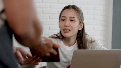 Indian waitress hands tablet to beautiful Asian woman working lunch at cafe.. Stock Footage 249615588