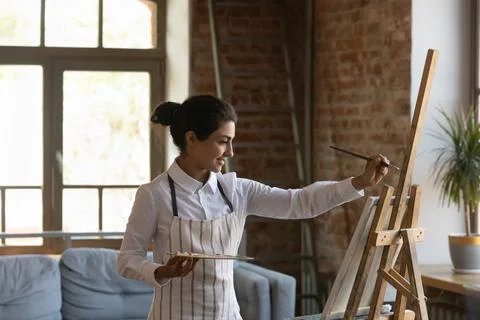 Indian woman painter painting on canvas in modern workshop Stock Photos