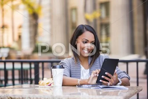 Indian Woman Reading Digital Tablet At Outdoor Cafe