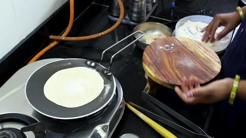 Indian Woman Rolling Roti While Chapati Cooks on Tawa | Multitasking Kitchen Stock Footage 336440934