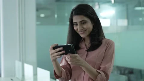 Indian woman standing while using smart phone watching funny videos. Stockbeeldmateriaal 170430335