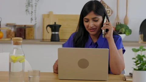 Indian woman talking on smartphone while working remotely Stock Footage 345096371