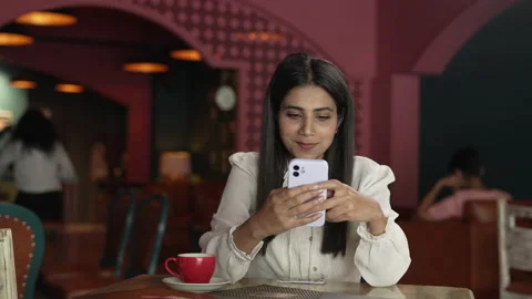  Indian woman while using smart phone for chatting with friends at the cafe.  Stock-Footage 232574480