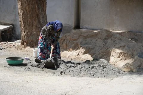 An indian woman worker is working her heavy labor day job at the construction Stock Photos