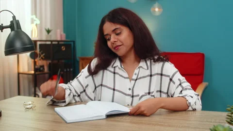 Indian woman writes notes in notebook then rereads careful study focused Stock Footage 315917475