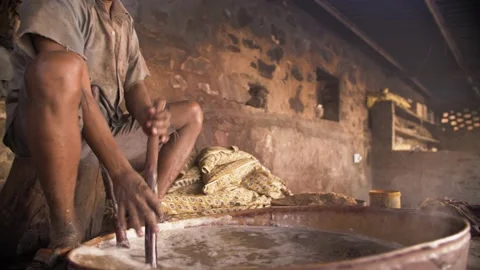 Indian worker dyeing block printed textiles in a pot with organic pigments. Video stock 151904693