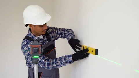 Indian worker in measuring wall with laser leveler at construction site Stock Footage 252943057
