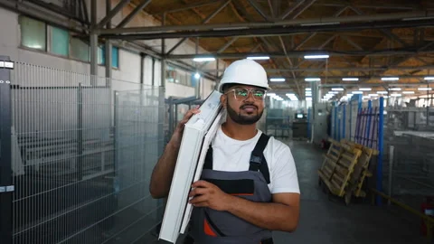 Indian worker walks with a window frame in a window factory near conveyor Stock Footage 283006776