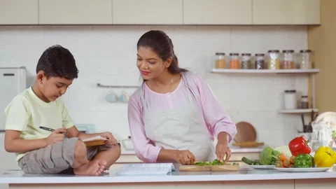 Indian working mother at kitchen helping her kid or child to do homework - Stock Footage 263718074