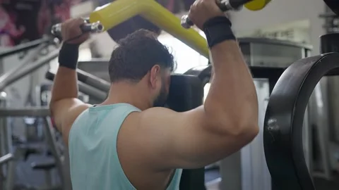 Indian young fit man performing shoulder exercise using machine in a modern gym Stock Footage 341856466