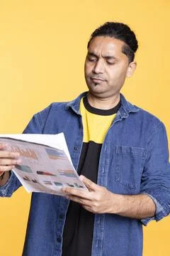 Indian young guy browsing though financial audit report paperwork Stock Photos