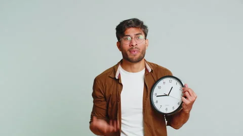 Indian young man with anxiety checking time on clock, running late to work Stock Footage 256086745