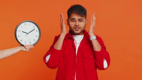 Indian young man with anxiety checking time on clock, running late to work Stock Footage 259492653