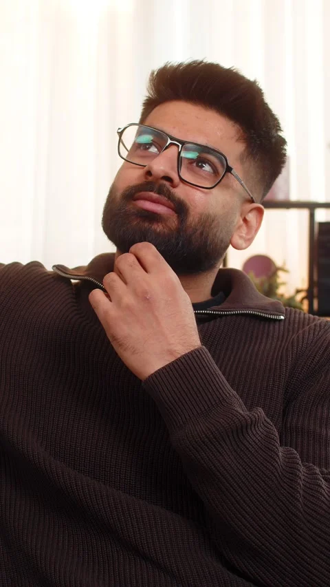 Indian young man on sofa at home looks at side with nostalgic face, thinking Stock Footage 314404790